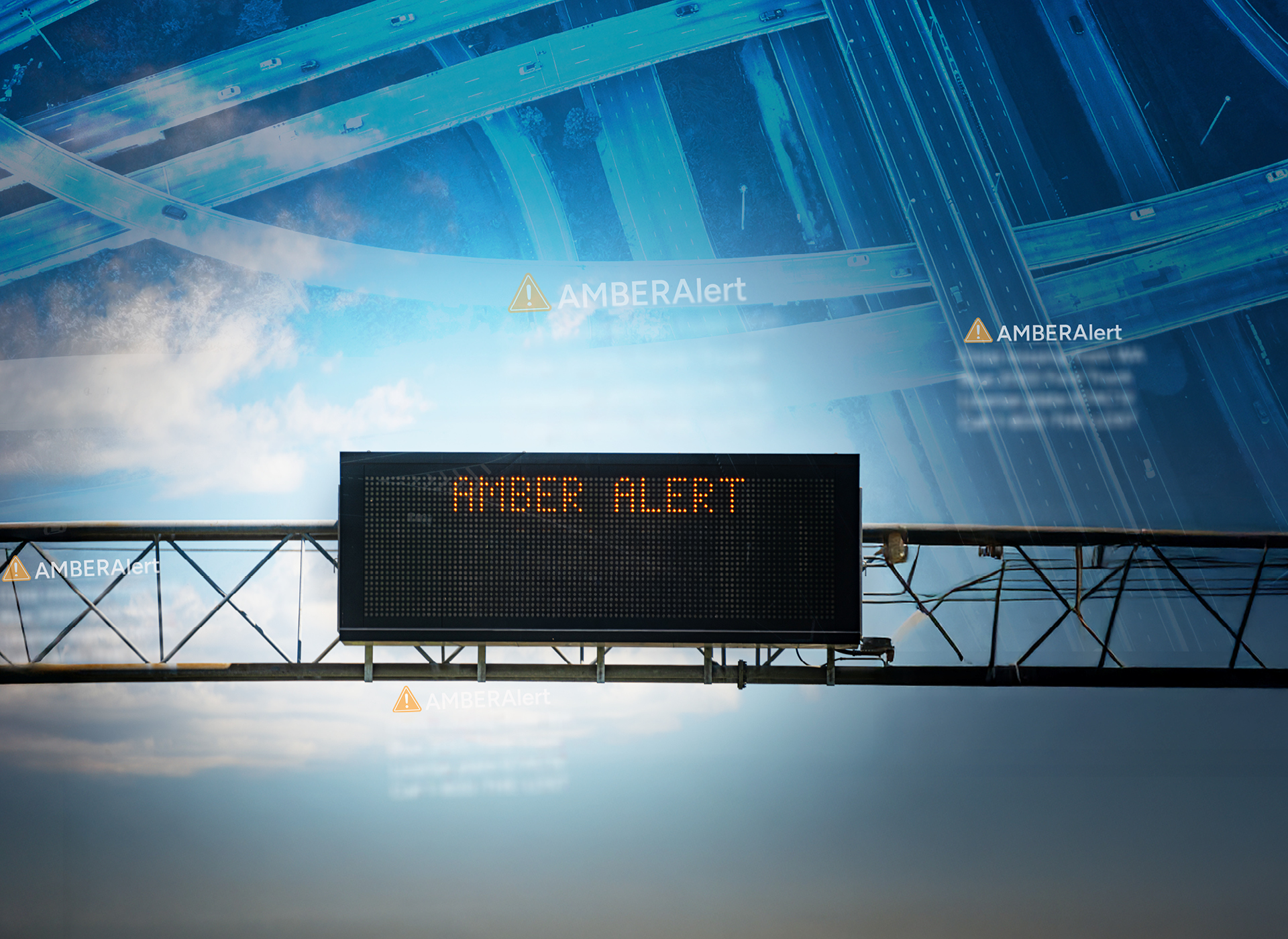 highway sign with amber alert in foreground; blue toned background of overhead shot of highway bypasses