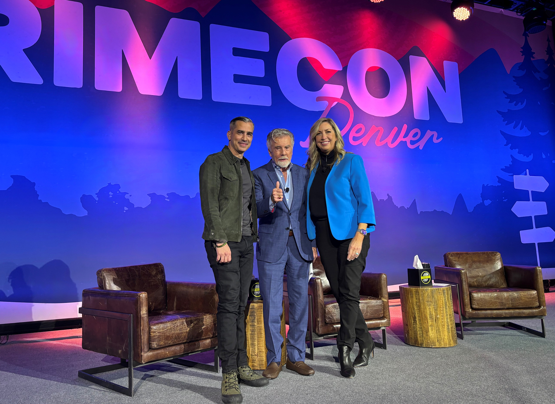 callahan walsh, john walsh, michelle delaune stand in front of crime con backdrop on stage