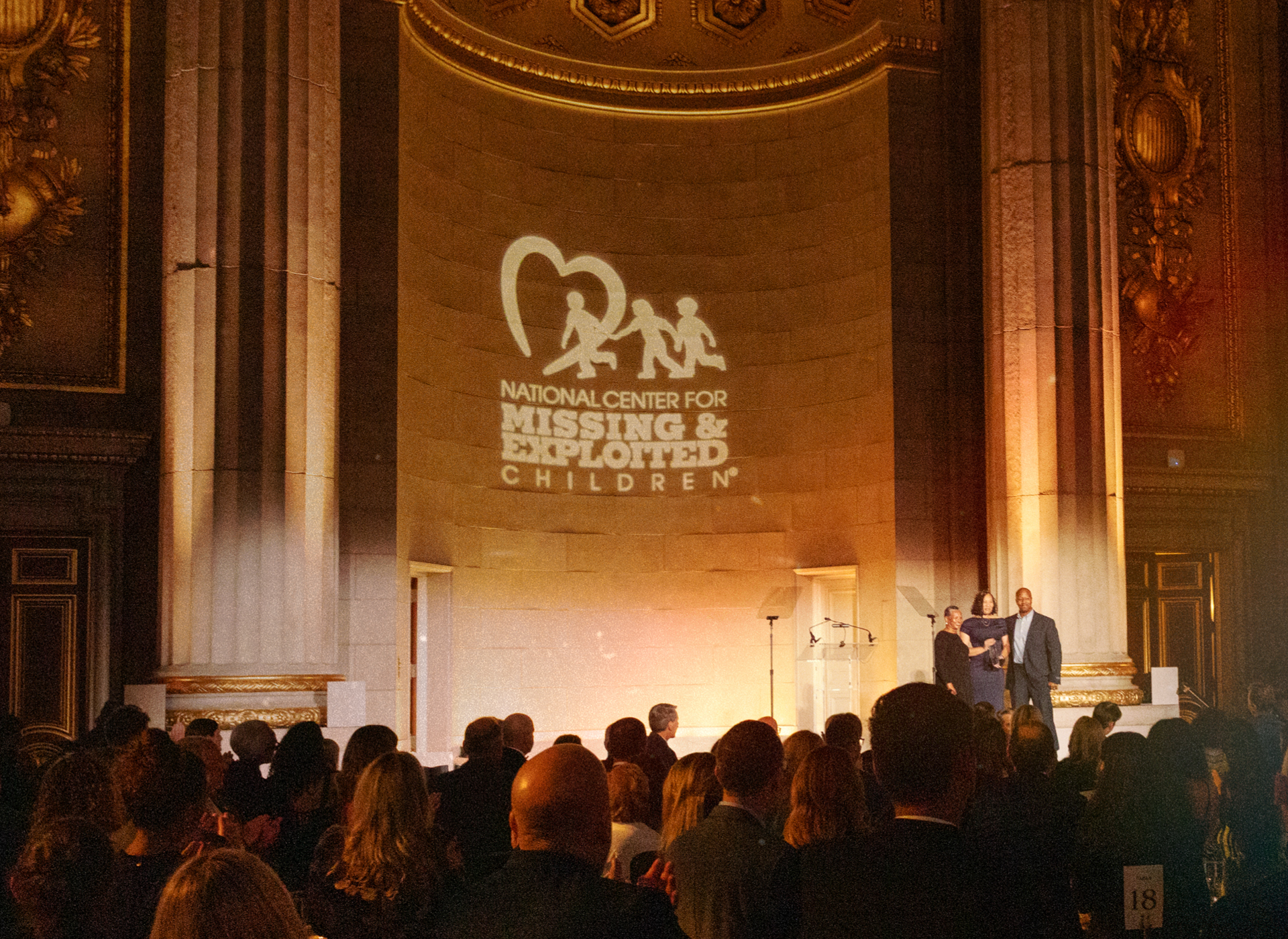 a couple stands on a stage in front of an audience